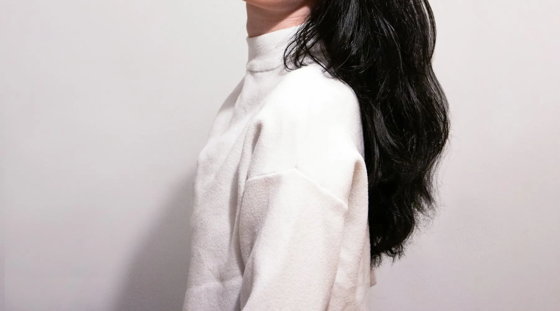 Model with long dark hair against a pink backdrop