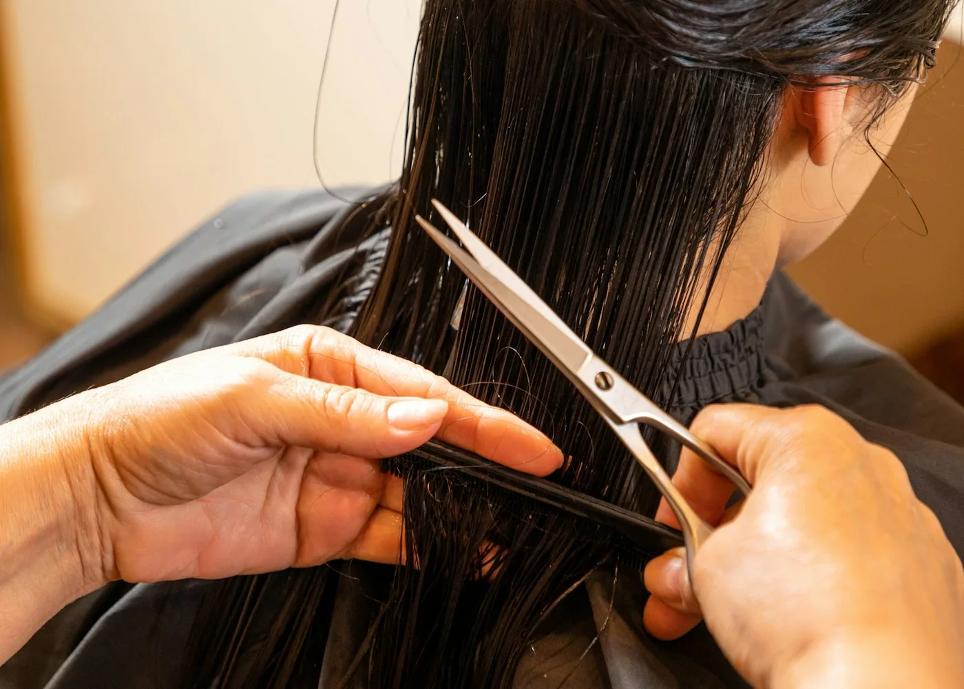 Stylist cutting wet hair with shears