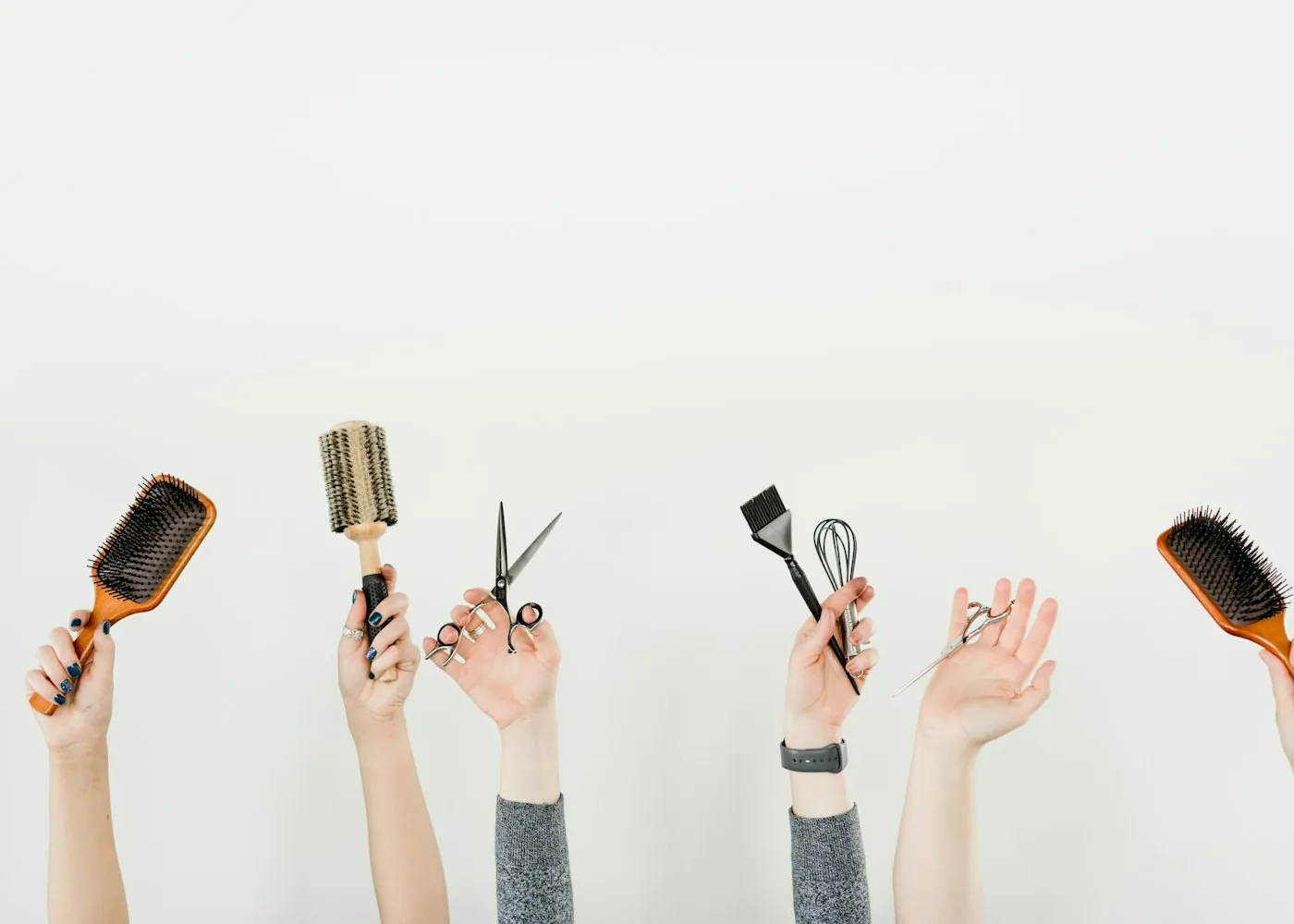 Hands holding brushes, shears and a tint brush